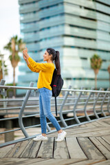 Full body young woman taking photo with camera phone