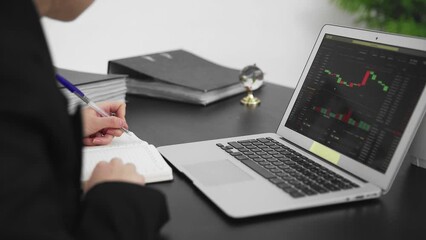 A close-up of the laptop screen, where a graph of bitcoin transaction statistics is visible. A business man
