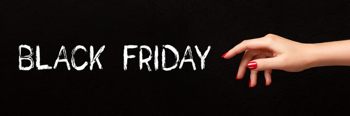 Wall Mural - Black Friday sign on black background with female hand with red nails banner. Wide panoramic header. Shopping concept