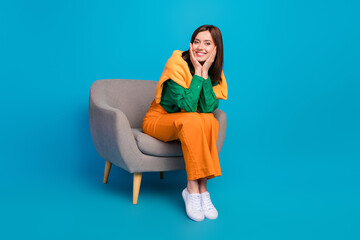 Full body photo of satisfied glad young lady sit chair arms touch cheeks isolated on blue color background