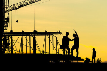 Silhouette of Engineer and worker checking project at building site background, construction site at sunset in evening time