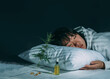 Asian girl sleeping in evening bedroom with cbd oil, capsules and a cannabis branch. Melatonin production, concept of combat sleep disorders. Dark background