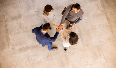 Wall Mural - Business people team stack hands as unity gesture in the office hallway