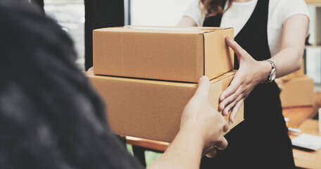 Closeup female hand accepting a delivery of boxes from deliverywoman.