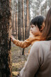 © Jakub - boy on mother's hands tearing bark off tree, selective focus