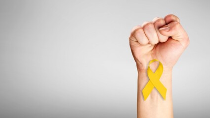 Canvas Print - Hand with yellow Ribbon on gray background