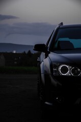 Sticker - Front view shot of a shiny luxury car outdoors under dark sunset sky