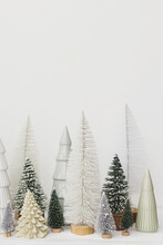 Merry Christmas And Happy Holidays! Stylish Little Christmas Trees On White Background. Festive Christmas Scene, Miniature Snowy Forest. Modern Minimal Scandi Decorations, Holiday Banner