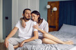 © saulich84 - couple in love in white clothes is sitting on the bed in the bedroom in the morning.