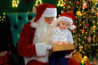 © ZaStock - Santa Clause reads Christmas tale to little boy while sitting near Christmas tree. New Year concept