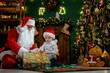 © ZaStock - Little boy opening his Christmas gift with Santa Claus. Christmas Scenes. New Year concept