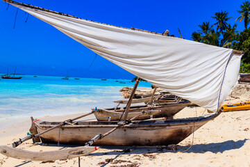 Canvas Print - Traditional wooden dhow boats ashore on tropical sandy Nungwi beach in the Indian ocean on Zanzibar, Tanzania