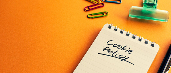 Poster - there is a notebook with the word cookie policy. it's placed on a color background.