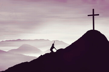 man crawling on the mountain toward cross symbol