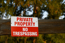 An Image Of A Red And White No Trespassing Sign Nailed To A Wooden Fence. 