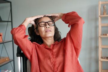 Wall Mural - portrait of a Asian woman in her 50s sitting on a chair and massage the head, 