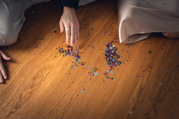 Two girls collect confetti stars from the floor for Christmas. Front view.