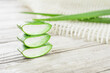 Close-up Fresh Aloe vera sliced with water drops on white wood background.