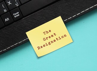 Wall Mural - On blue background, keyboard with stick note written THE GREAT RESIGNATION, the BIG QUIT trend where millions of American employees voluntarily quit their jobs  after pandemic for work life balance