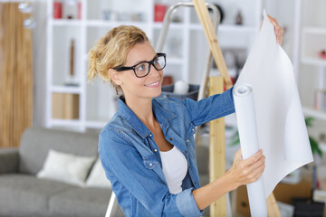 Wall Mural - woman unrolling a wall paper on the wall