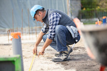 Construction Worker Measuring Foundations At Site