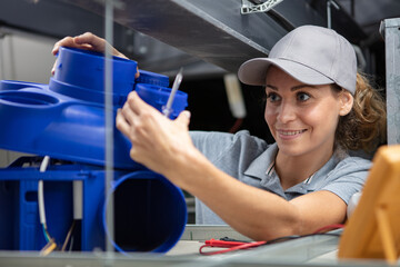 young female worker installing plastic ventilation unit