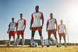 © Allistair F/peopleimages.com - Soccer player, team and sports training on soccer field by men standing with ball, power and strong mindset. Football, fitness and man football players united in support on football field for workout