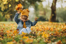 Cute Boy Playing With Leaves In Autumn Park