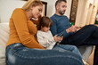 © Svitlana - Young family watching digital tablets at home