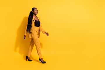 Wall Mural - Full length body size view of attractive cheerful girl agent broker going copy blank space isolated on bright yellow color background