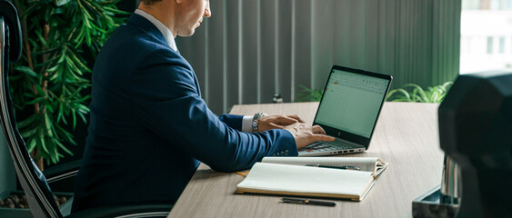 Businessman working with laptop in modern office. General manager,ceo. Young handsome confident man in suit sitting at table. Executive business leader. Entrepreneur career.Accountant bank workplace