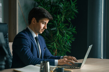 Businessman working with laptop in modern office. General manager,ceo. Young handsome confident man in suit sitting at table. Executive business leader. Entrepreneur career.Accountant bank workplace