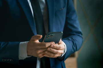 Businessman in suit with mobile phone in hands. Man typing message, using social net. Checking news. Making business meeting. Modern office.General manager,ceo.Calling to partner.Planning working day