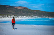 beautiful long-haired girl walks at sunset on the famous lucky bay beach in western australia; sunset on paradise beach with mountains in the background