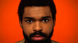 close up of young and bearded african american man with brown eyes isolated on orange.