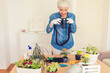 © Jelena Stanojkovic - A mature woman uses her camera to take pictures of her plants at home during the day.
