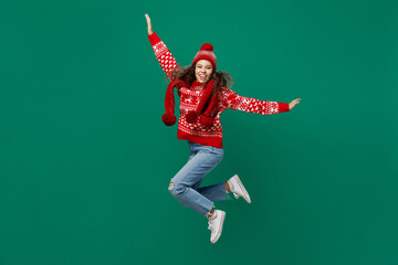 Wall Mural - Full body fun merry young woman wear red warm cozy knitted sweater hat posing jump high with outstretched hands isolated on plain dark green background Happy New Year 2023 celebration holiday concept