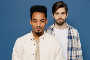 Young two friends attractive fashionable cool men 20s wearing white casual shirts together looking camera isolated plain dark royal navy blue color background studio portrait People lifestyle concept