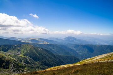 Sticker - View of white clouds and blue sky over layered mountain ranges and valley covered with vegetation