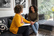 An African-American female psychotherapist comforts the teenage female patient by holding her hands. Both of them have the afro hairstyle.