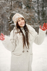 Teenager girl in red gloves standing at winter park and posing for a photo