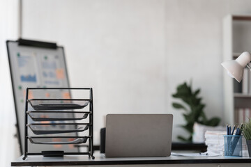 Modern workspace laptop and notebook on white table with blurred office room background.