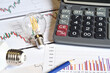 © Dan74 - Close up of energy saving light bulbs, calculator and pencil on printed graph. Concept for the rising cost of electricity. Expensive energy bill and rising electricity prices.