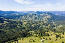 View Of Layered Mountain Ranges Covered With Dense Pine Forest And Green Valley Under Blue Sky