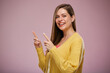 © Yuriy Shevtsov - Smiling woman in yellow sweater pointing fingers up. Advertising fefemale portrait.