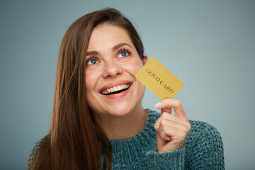 Happy laughing woman wearing green sweater holding credit card.  Advertising female portrait.