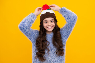 Modern teen girl wearing sweater and knitted hat on isolated yellow background. Happy teenager, positive and smiling emotions of teen girl.