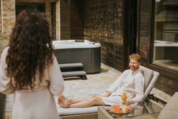 Young couple relaxing on beds and drinking fresh orange juice on the outdoor terrace