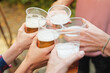 Group of four young friends cheering with beer in plastic glasses, celebrating their friendship, autumn surrounding