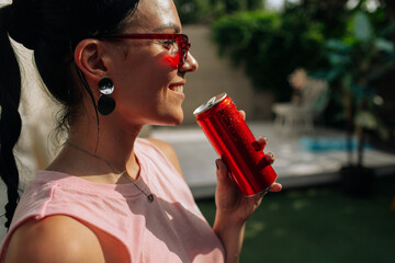 A girl on an orange background with a red tin can in her hands. Cheerful girl, advertising shooting. High quality photo